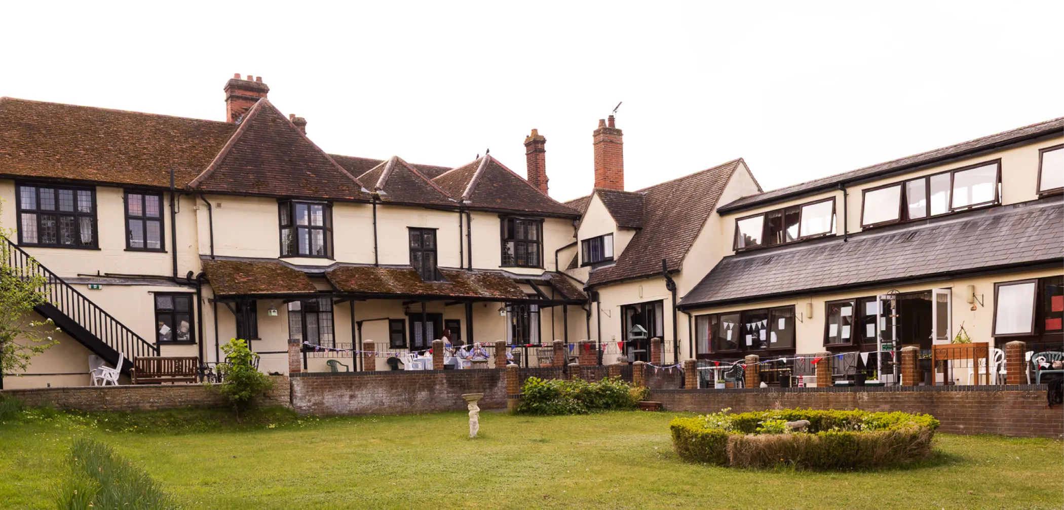 Exterior view of a traditional residential care home with garden lawn.